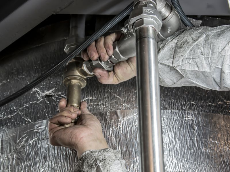 Hands tightening a pipe fitting with a wrench